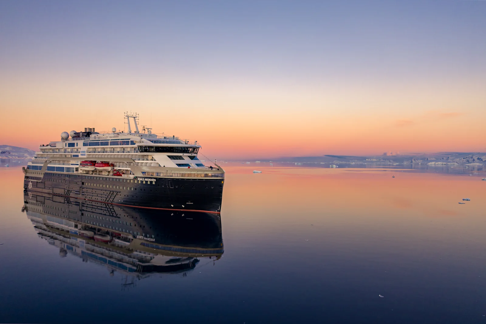 MS Roald Amundsen reflected in calm Antarctic water at sunset