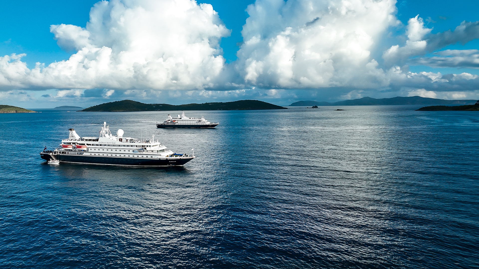 Two SeaDream Yacht Club yachts anchored beside tropical islands